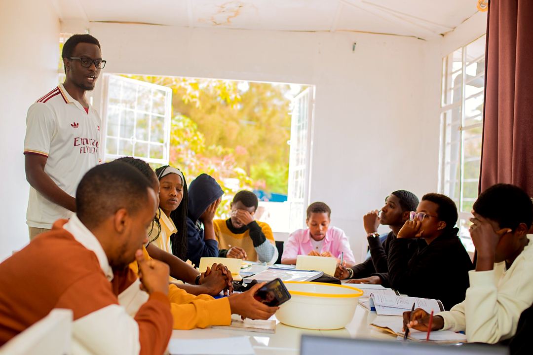 An instructor leading a German class around a shared table in a bright classroom